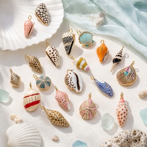 Könnte beinhalten: Eine Sammlung verschiedener muschelförmiger Metallanhänger mit farbenfrohen Emaille-Mustern, darunter gepunktete, gestreifte und texturierte Designs. Jeder Anhänger hat eine kleine goldfarbene Öse an der Oberseite zur Befestigung und zeigt vielfältige, von Meeresbewohnern inspirierte Formen.