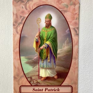 Op de afbeelding: Een religieuze kaart met een afbeelding van Sint-Patrick. De afbeelding toont Sint-Patrick in groene en gouden gewaden, met een staf. De achtergrond heeft een bloemenontwerp en de tekst "Saint Patrick".