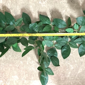 May include: A white ceramic mug with a black handle and the text "But First, Coffee" in a bold, black font. The mug is set against a blurred background, suggesting a cosy setting.