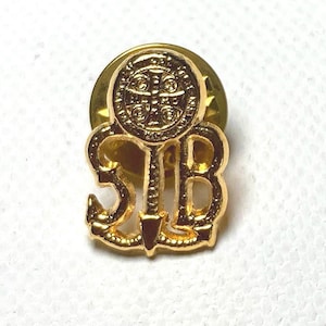 Puede incluir: Un pin de solapa dorado con las letras "SIB" y un diseño de ancla. El pin tiene un emblema circular en la parte superior con un diseño de cruz. El pin está sobre un fondo blanco.