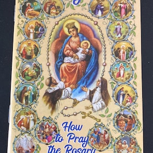 May include: A beige booklet titled "Rosary Prayers" with illustrations of religious figures. The cover features a central image of Mary and baby Jesus, surrounded by smaller images depicting scenes from the Bible. Text on the cover reads "How to Pray the Rosary."
