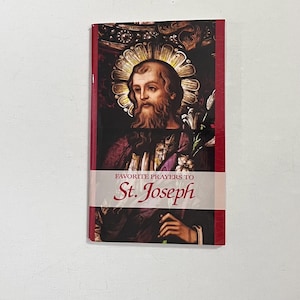 Könnte beinhalten: Ein Buch mit dem Titel "Favorite Prayers to St. Joseph" zeigt eine Illustration von St. Joseph mit Heiligenschein und Bart. Das Buch hat einen roten Buchrücken und ein weißes Band mit dem Titel. Der Hintergrund ist ein dunkles, verziertes Design.