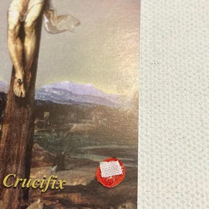 Könnte beinhalten: Religiöses Bild, das die Kreuzigung Jesu Christi darstellt. Das Kunstwerk zeigt Jesus an einem Holzkreuz, mit einem Landschaftshintergrund. Das Wort "Crucifix" ist in goldener Schrift unten links gedruckt.