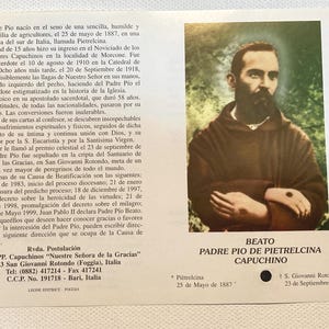 May include: A printed card featuring a portrait of Padre Pio, a Capuchin friar. The image shows a man with a beard and a brown robe. Text in Spanish details his life and beatification.