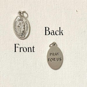 May include: Two silver oval pendants. One pendant features an image of an angel with the words "ARCHANGEL RAPHAEL". The other pendant has the words "PRAY FOR US". The pendants are shown against a white background.