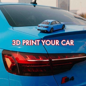 May include: A bright blue scale model sedan car resting on the boot of a matching full-sized blue sedan. The text 3D PRINT YOUR CAR is displayed in red letters across the centre of the image, positioned above the rear taillight assembly.