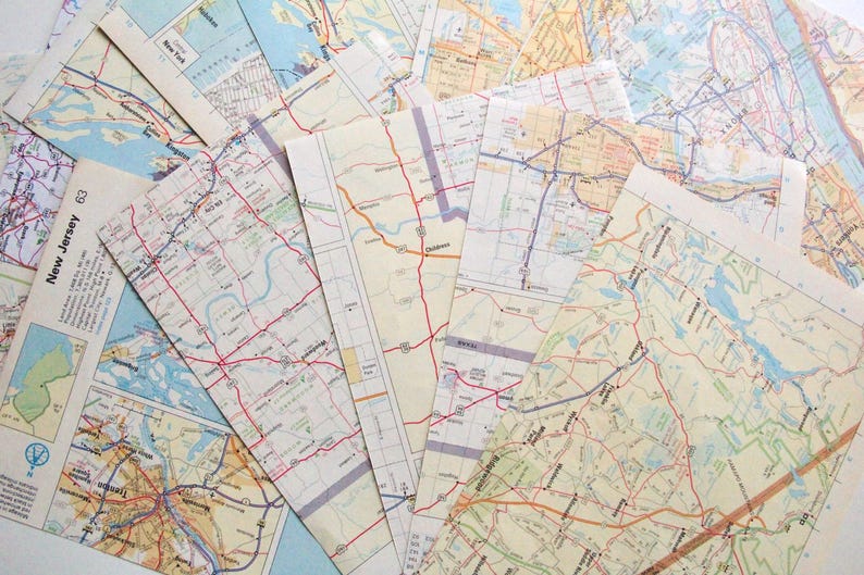 May include: A selection of vintage road maps, spread out to show their details. The maps feature a variety of colours, including shades of blue, green, yellow, and red, with intricate road networks and geographical features.