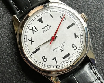 Reloj mecánico HMT Pilot vintage con esfera blanca, números romanos y 17 rubíes de cuerda manual.