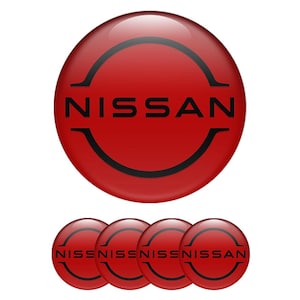 Puede incluir: Un conjunto de emblemas circulares rojos y brillantes con la palabra "NISSAN" en negro y un diseño curvo negro. La imagen incluye un emblema grande y cuatro más pequeños, todos con el mismo diseño.