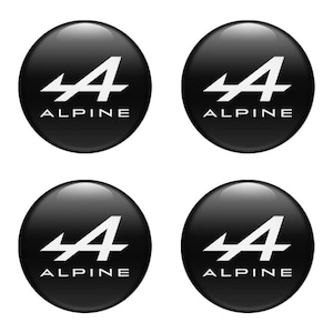 Könnte beinhalten: Vier schwarze, glänzende, kreisförmige Aufkleber. Jeder Aufkleber zeigt das weiße Alpine-Logo, einen stilisierten Buchstaben "A" über dem Wort "ALPINE" in Weiß, zentriert auf dem schwarzen Hintergrund. Die Aufkleber sind quadratisch angeordnet.