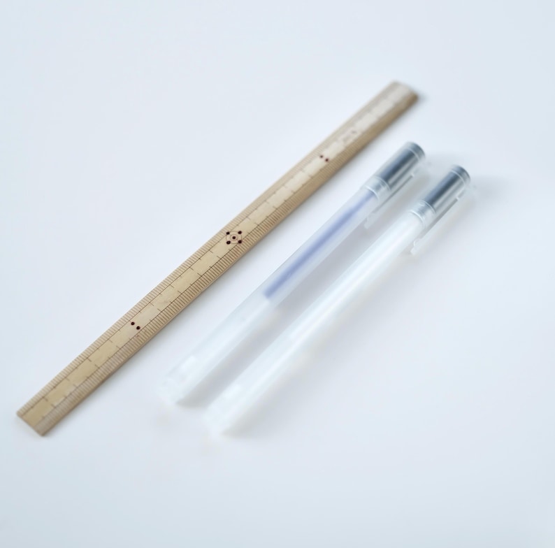 May include: Two clear plastic pens and a wooden ruler with black markings. The ruler is about 12 inches long.