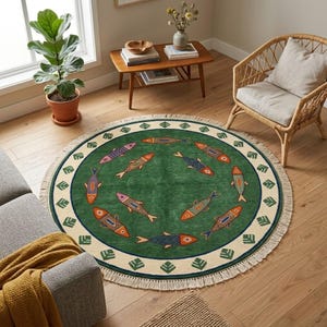 Pode incluir: Um tapete redondo com um centro verde profundo decorado com um padrão de peixes multicoloridos. O tapete tem uma borda larga de cor creme com motivos de folhas verdes repetidos e um acabamento com franjas em toda a circunferência.