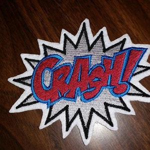 May include: A white, red, and blue embroidered patch with a starburst design and the word "Crash!" in bold letters.