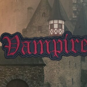 May include: A red embroidered patch with the word "Vampire" in a gothic font on a black background.