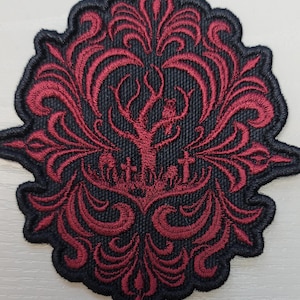 May include: Embroidered patch with a black background and a red damask design. The patch features a tree, tombstones, and a decorative border. The patch is likely for clothing or accessories.