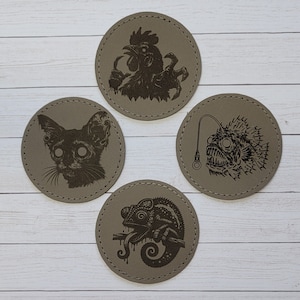 May include: Set of four brown leather coasters with black engraved images of a rooster, a cat, a fish, and a chameleon.