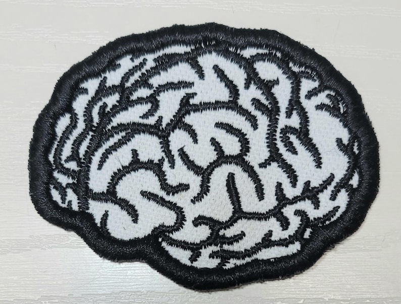 Pode incluir: Patch bordado em forma de c&eacute;rebro. O patch apresenta um fundo branco com linhas pretas bordadas que representam a estrutura do c&eacute;rebro. O patch &eacute; delineado com uma borda preta espessa.