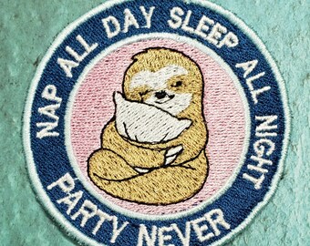 Op de afbeelding: Gestikte patch met een luiaard die een kussen vasthoudt. De patch is blauw met witte tekst die "Nap All Day Sleep All Night Party Never" luidt.