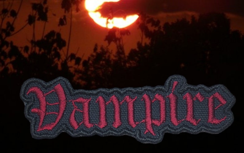 May include: A black and red embroidered patch with the word "Vampire" in a gothic font.