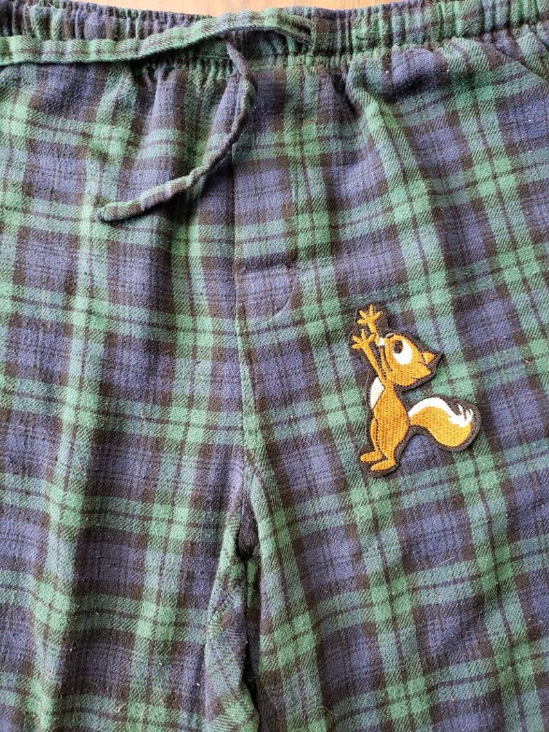 Peut inclure: Pantalon de pyjama en tissu &eacute;cossais vert et bleu avec une applique de  &eacute;cureuil marron.
