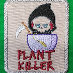 May include: Embroidered patch with a cartoon Grim Reaper wearing a black hooded robe and holding a scythe. The Grim Reaper is sitting in a purple pot with the text "PLANT KILLER" in red.