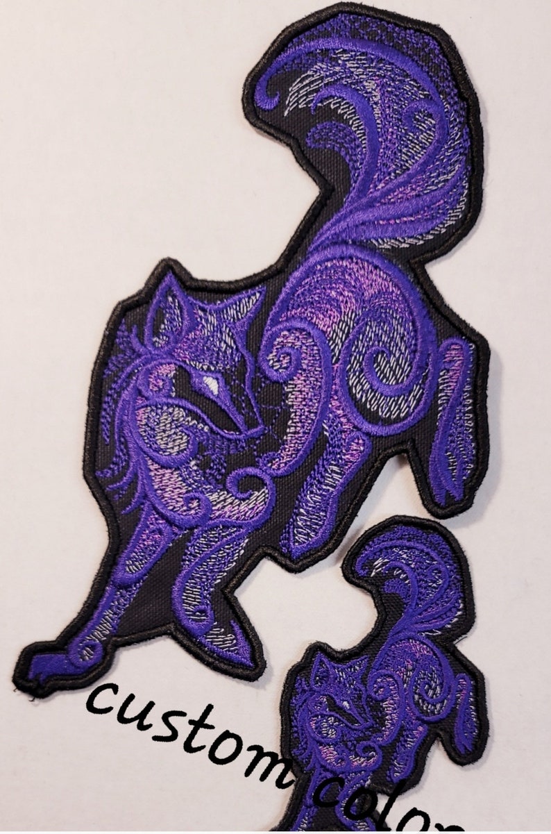 May include: Purple embroidered iron-on patch of a stylized wolf with a curled tail. The wolf is outlined in black and has a swirling pattern.