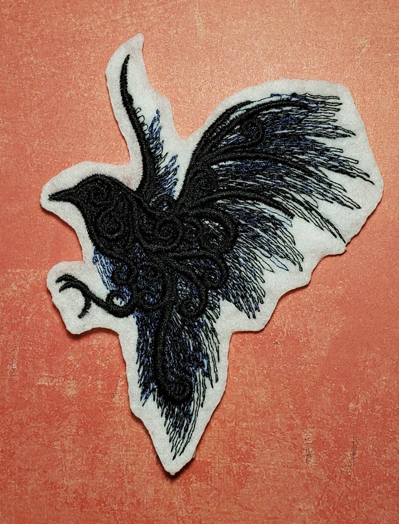 May include: Black embroidered patch of a rooster with its wings spread out. The rooster is facing to the right and has a detailed design.