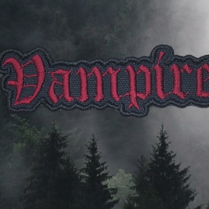 May include: Black and red embroidered patch with the word "Vampire" in a gothic font.