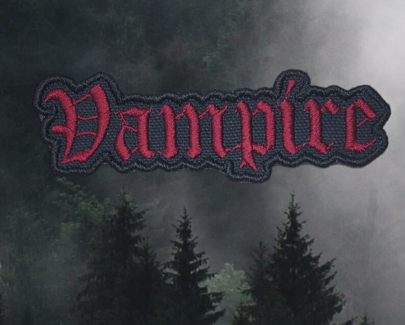 May include: Black and red embroidered patch with the word "Vampire" in a gothic font.