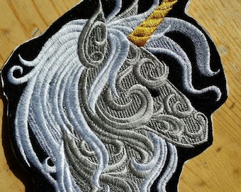 May include: Embroidered iron-on patch of a white unicorn head with a gold horn on a black background.