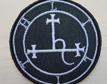 May include: A black embroidered patch with a white sigil. The sigil is a circle with a cross inside, and a letter 'L' at the top and bottom of the circle. The sigil is surrounded by a circle with the letters 'H' and 'I' at the top and bottom.
