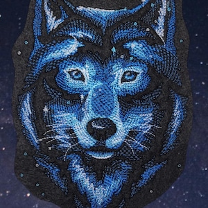 May include: Blue embroidered wolf head patch with a starry night background. The wolf's fur is a dark blue with white highlights, and its eyes are a bright blue.