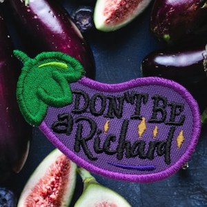 May include: Purple eggplant-shaped embroidered patch with the text "Don't be a Richard" in black lettering with yellow accents. The patch is surrounded by purple eggplants and green figs.