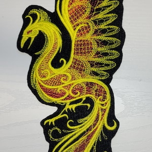 May include: Yellow and red embroidered phoenix patch with intricate details. The phoenix is depicted with its wings spread and a long tail.
