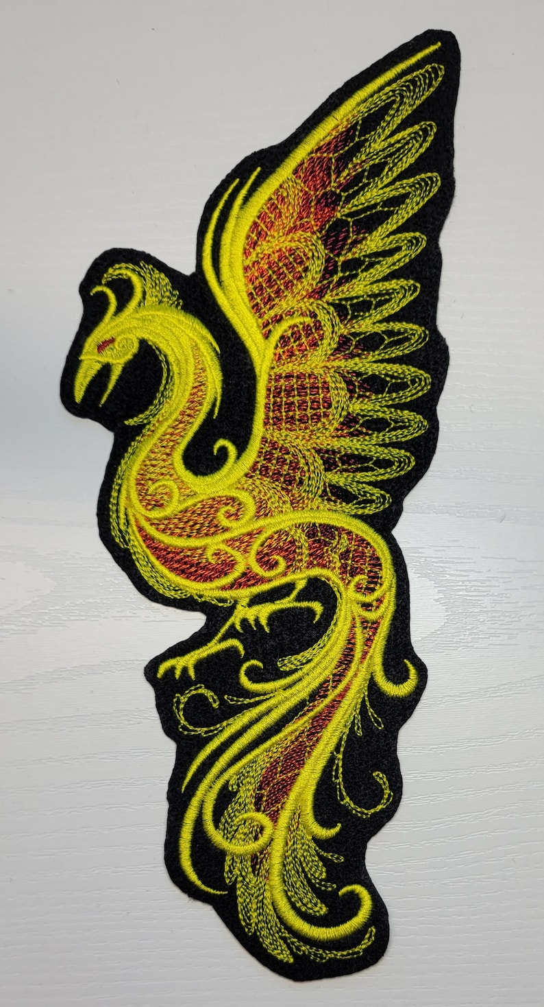 May include: Yellow and red embroidered phoenix patch with intricate details. The phoenix is depicted with its wings spread and a long tail.