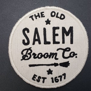 May include: White circular patch with black text that reads "The Old Salem Broom Co. Est 1677" with a stylized broom and stars.