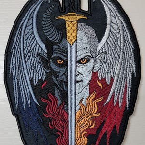 May include: Embroidered patch featuring a sword piercing through the faces of an angel and a devil. The angel has white wings and the devil has black wings. The sword is gold and the background is black.