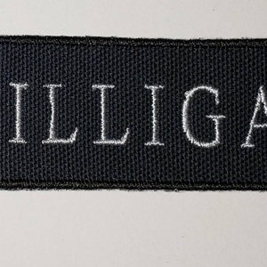 May include: Black embroidered patch with white stitching that reads "DILLIGAF".