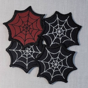 May include: Four embroidered iron-on patches featuring a spider web design. One patch is red with black stitching, and the other three are black with white stitching.