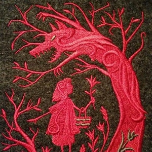 May include: Red embroidered design of a wolf and a girl in a red hood standing in a forest. The wolf is depicted as a tree with a wolf's head and the girl is holding a basket.