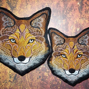 Peut inclure: Deux patchs brod&eacute;s en forme de t&ecirc;te de renard avec des motifs complexes dans des tons de brun, orange et blanc. Le plus grand patch est l&eacute;g&egrave;rement plus grand que le plus petit.