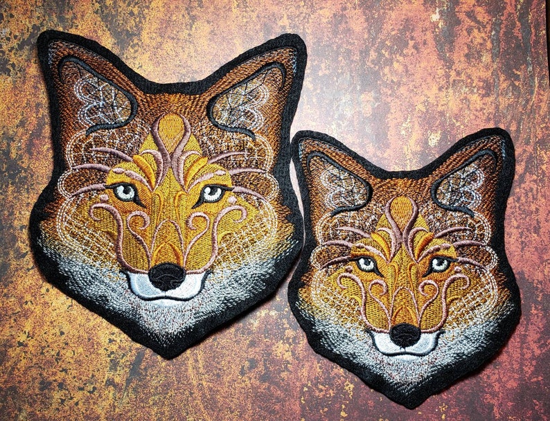 Peut inclure: Deux patchs brod&eacute;s en forme de t&ecirc;te de renard avec des motifs complexes dans des tons de brun, orange et blanc. Le plus grand patch est l&eacute;g&egrave;rement plus grand que le plus petit.