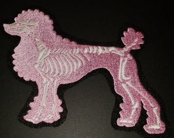 May include: Pink embroidered patch of a poodle with a white skeleton design.