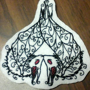 May include: Embroidered patch featuring a black and white stylized bat with red eyes. The bat is surrounded by intricate black swirls and designs on a white background.