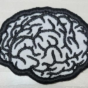 May include: Embroidered patch in the shape of a brain. The patch features a white background with black embroidered lines depicting the brain's structure. The patch is outlined with a thick black border.