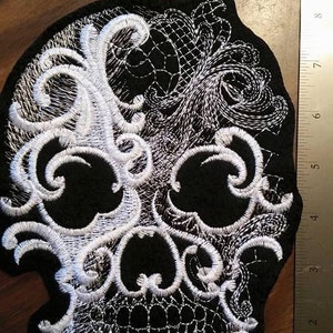 May include: Black fabric skull patch with white embroidered lace design.
