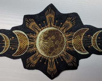 May include: A black felt patch with gold embroidery of a sun and three crescent moons. The sun has a radiating design and the moons are in different phases.