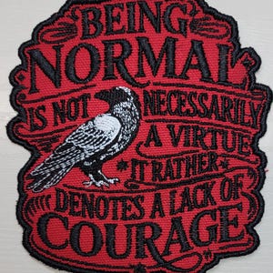 May include: A red embroidered patch with a black border featuring a black and white crow illustration. The text reads: BEING NORMAL IS NOT NECESSARILY A VIRTUE IT RATHER DENOTES A LACK OF COURAGE. The design uses black thread for the lettering and decorative swirls.