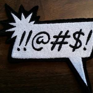 May include: White embroidered patch with a black border in the shape of a speech bubble with a starburst behind it. The text inside the speech bubble reads "!!@#$".