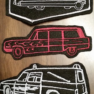May include: Three embroidered patches featuring different styles of hearses. The first patch is black with a white outline of a hearse in a coffin shape. The second patch is black with a red outline of a hearse with flames on the side. The third patch is black with a white outline of a hearse with a roof.